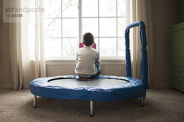 Rückansicht des auf dem Trampolin sitzenden Jungen