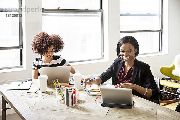 Geschäftsfrauen mit Laptop und Tablet-Computer am Schreibtisch im Kreativbüro