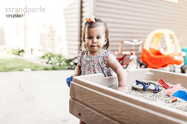 Porträt eines kleinen Mädchens beim Spielen mit Sand im Hinterhof