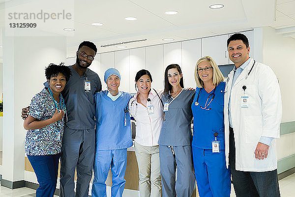 Porträt von fröhlichen Ärzten und Krankenschwestern im Krankenhauskorridor stehend
