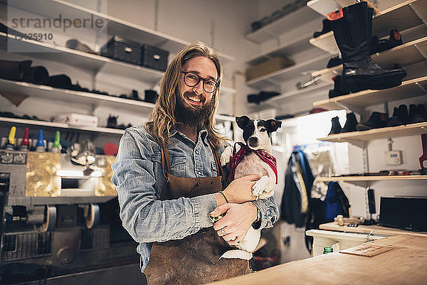 Porträt eines lächelnden Schuhmachers mit Hund bei einem Workshop