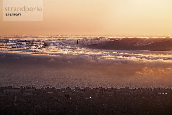 Digitales zusammengesetztes Bild von Wellen und Stadt bei Sonnenuntergang