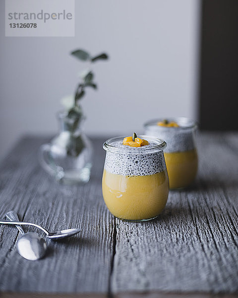 Dosen Chia mit Mangopudding auf Holztisch