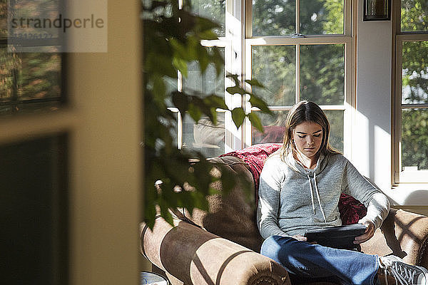 Frau benutzt Tablet-Computer  während sie zu Hause auf dem Sofa sitzt