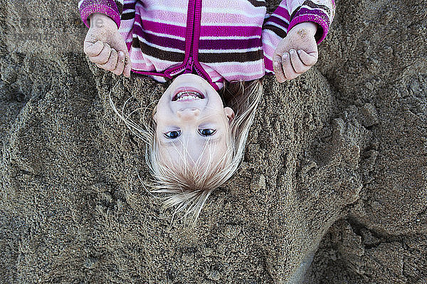 Portrait eines am Sandstrand liegenden Mädchens