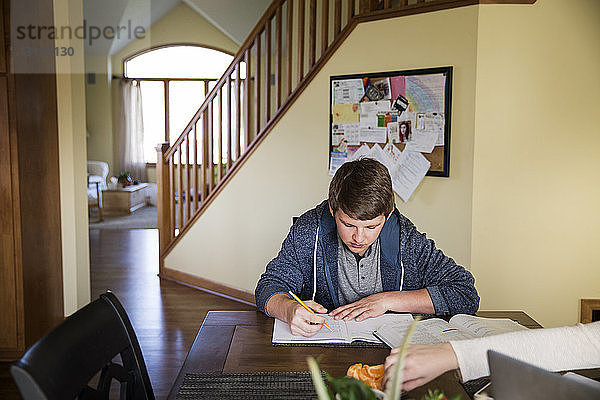 Junger Mann lernt zu Hause auf dem Tisch