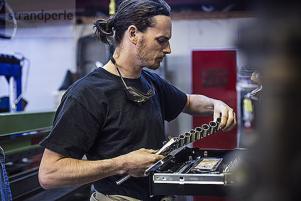 Mechaniker hält Handwerkzeug in der Autowerkstatt
