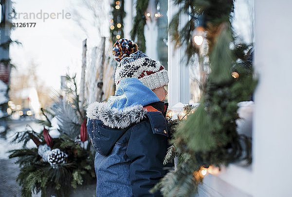 Seitenansicht eines Jungen in warmer Kleidung  der am Haus steht