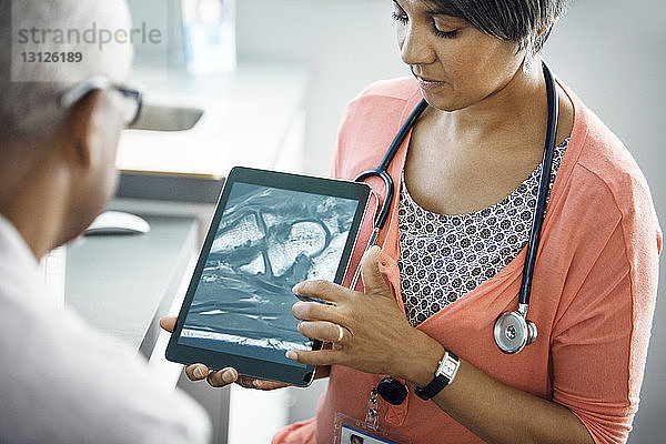 Ärztin erklärt Patientin das Röntgenbild am Tablet-Computer in der Klinik