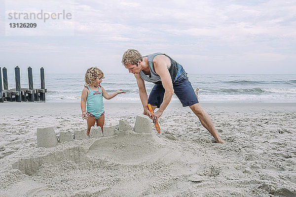 Vater baut Sandburg von Tochter am Cape May Beach gegen den Himmel