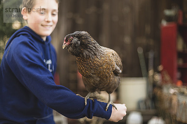 Nahaufnahme eines Jungen  der auf einer Geflügelfarm mit Hühnern spielt