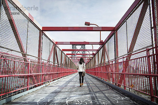 Rückansicht einer jungen Frau  die über die Williamsburg Bridge geht