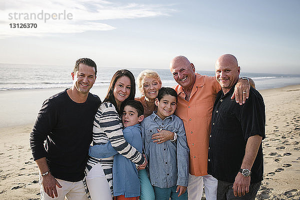 Porträt einer glücklichen Familie  die am Strand gegen den Himmel steht