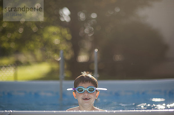 Porträt eines glücklichen Jungen mit Schwimmbrille im Schwimmbad