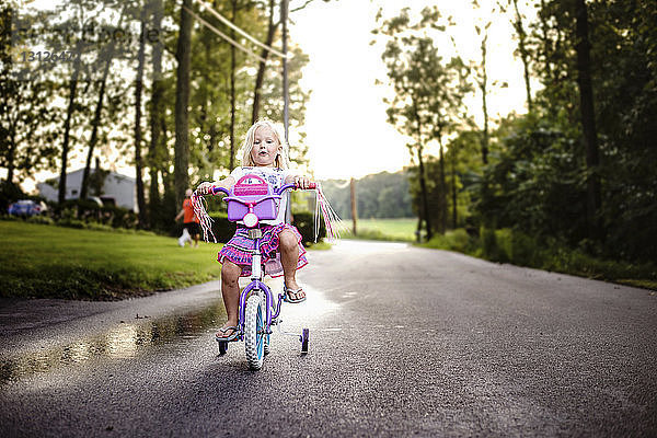 Mädchen fährt Fahrrad auf Straße im Park
