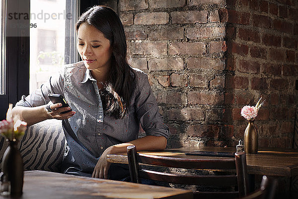 Frau benutzt Smartphone  während sie im Café sitzt