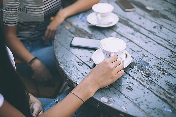 Mitsektion von Freunden mit Kaffee auf dem Tisch sitzend im Straßencafé