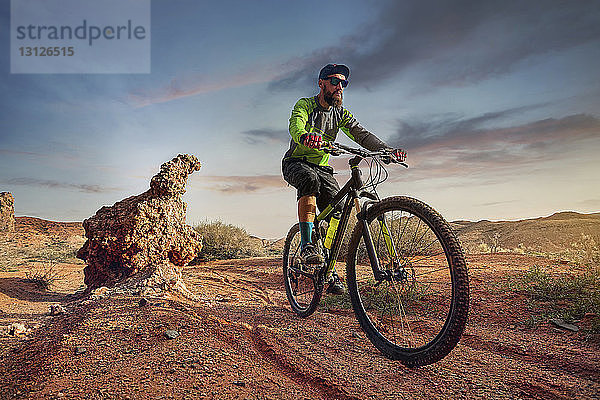 Wandern mit dem Mountainbike in der Wüste gegen den Himmel bei Sonnenuntergang
