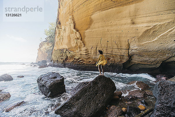 Seitenansicht einer auf einem Felsen stehenden Frau auf der Insel Réunion