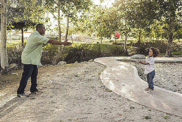 Vater und Sohn spielen mit dem Ball im Park