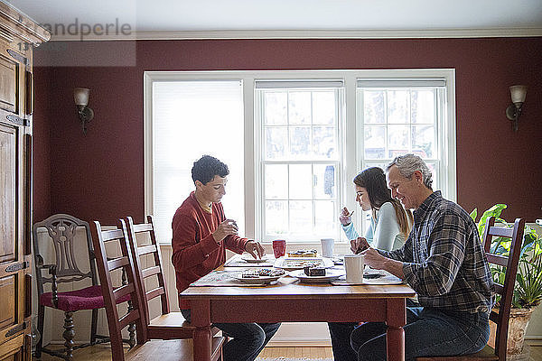 Glückliche Familie frühstückt zu Hause am Tisch