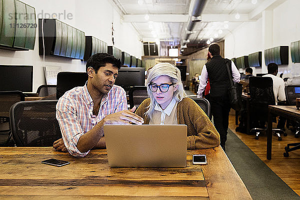 Geschäftsleute  die während der Arbeit am Laptop im Kreativbüro diskutieren