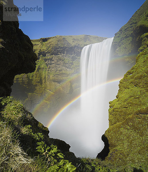 Szenenansicht der Regenbögen über dem Wasserfall Skogafoss vor klarem Himmel