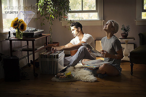 Glückliches junges Paar wählt zu Hause Vinyl-Schallplatte