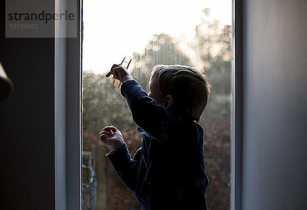 Junge spielt mit Spielzeug  während er zu Hause am Fenster sitzt