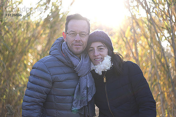 Porträt eines reifen Paares in warmer Kleidung auf dem Feld bei sonnigem Wetter