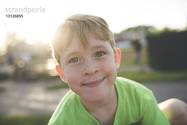 Porträt eines süßen  lächelnden Jungen  der bei Sonnenuntergang auf dem Spielplatz spielt