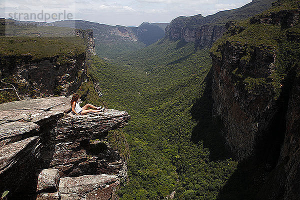 Blick aus mittlerer Entfernung auf eine Frau  die auf einer Klippe im Nationalpark Chapada Diamantina sitzt