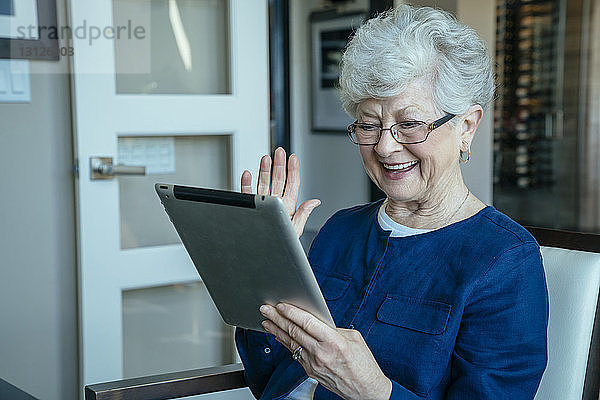 Glückliche ältere Frau bei Videokonferenzen über Tablet-Computer zu Hause