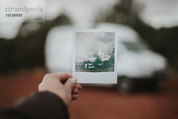 Geschnittene Hand einer Frau  die ein Foto gegen ein Wohnmobil hält