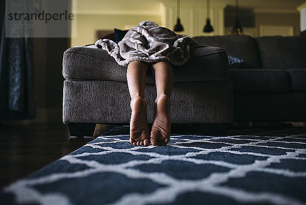 Niedriger Teil eines Jungen  der zu Hause auf dem Sofa liegt