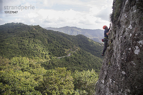 Seitenansicht eines Wanderers beim Felsklettern gegen Berge