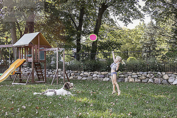 Verspieltes Mädchen wirft Frisbee mit Hund auf dem Spielplatz