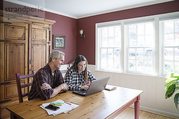 Großvater und Enkelin mit Laptop-Computer am Tisch zu Hause