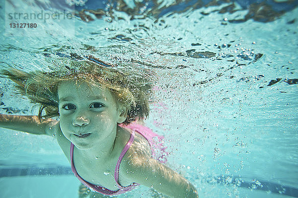 Porträt eines Mädchens  das im Pool unter Wasser schwimmt