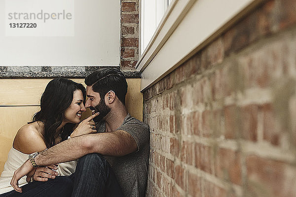 Glückliches Paar  das zu Hause an der Wand sitzt