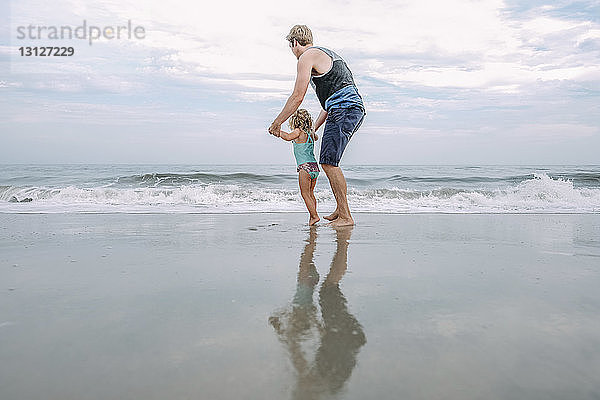 Seitenansicht von Vater und Tochter beim Spiel am Cape May Beach gegen den Himmel