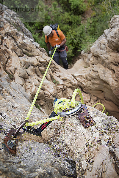 Hochwinkelaufnahme eines Mannes  der sich am Felsen abseilt