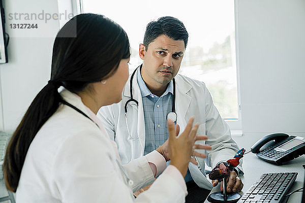 Ärztin bespricht anatomisches Herzmodell mit männlichem Kollegen im Krankenhaus