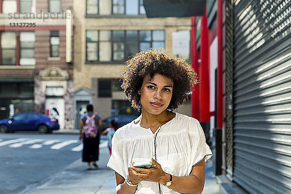 Porträt einer Frau mit Smartphone in der Hand in der Stadt