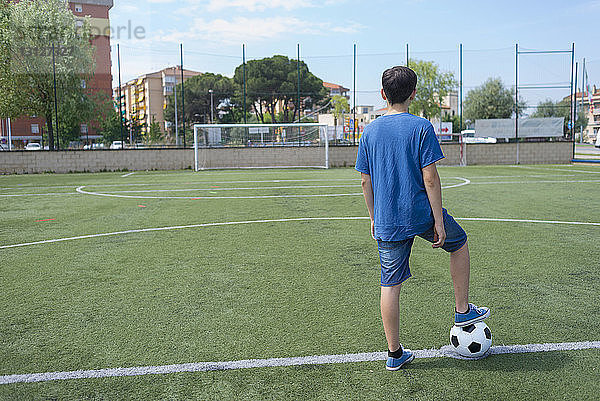 Rückansicht eines Jungen beim Fussballspielen auf dem Feld gegen den Himmel