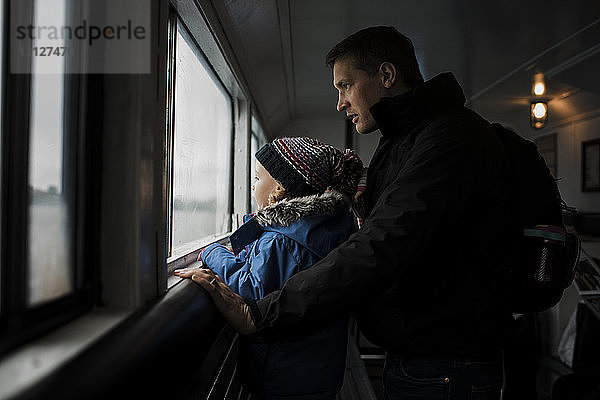 Vater und Tochter schauen durchs Fenster