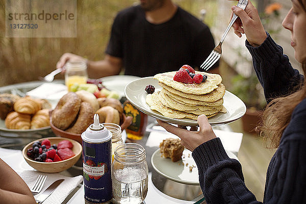 Junge Frau isst Pfannkuchen beim Frühstück mit Freunden