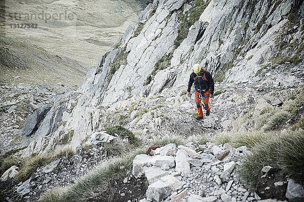 Hochwinkelaufnahme eines Wanderers  der beim Bergsteigen auf Felsen geht
