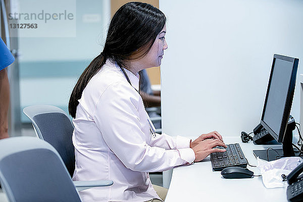 Seitenansicht einer Ärztin  die einen Desktop-Computer im Krankenhaus benutzt