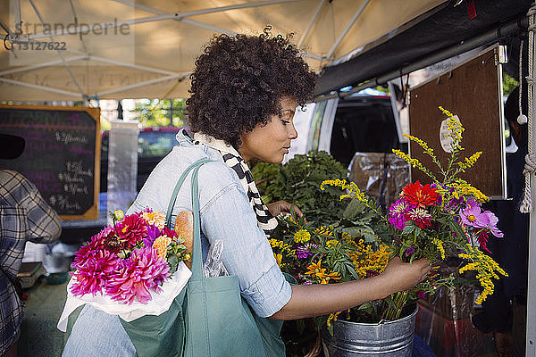 Frau wählt Blumen aus Container auf dem Markt aus